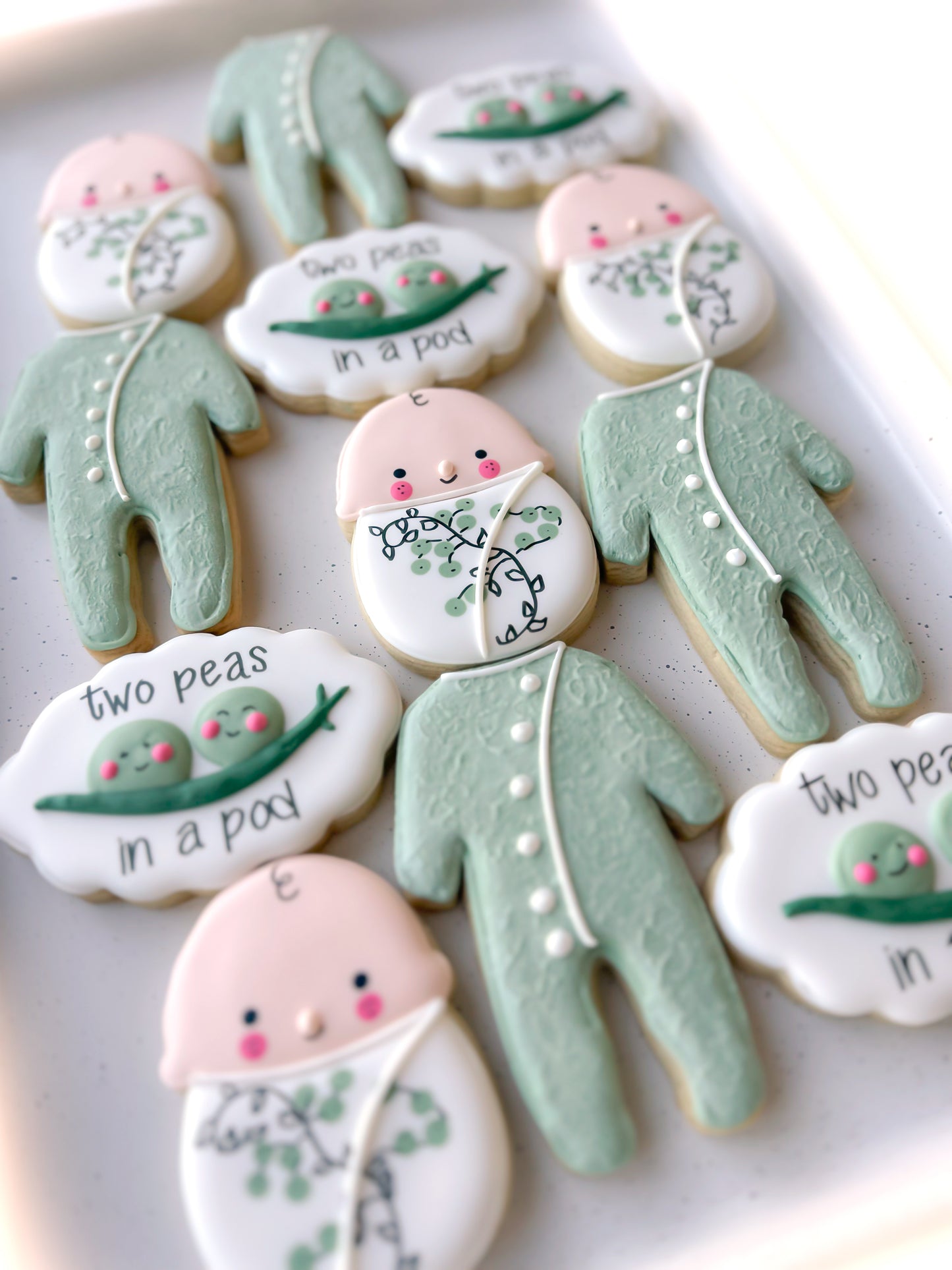 two peas in a pod, swaddled baby, crib mobile, footed pajamas, cat toy, baby shower cookies