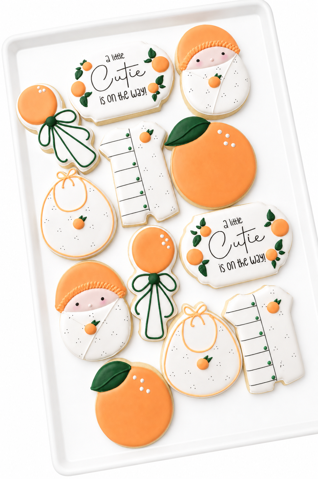 a little cutie on the way, orange rattle, bib, swaddled baby, romper, baby shower cookies