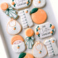 a little cutie on the way, orange rattle, bib, swaddled baby, romper, baby shower cookies
