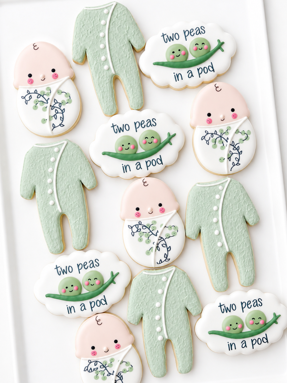two peas in a pod, swaddled baby, crib mobile, footed pajamas, cat toy, baby shower cookies