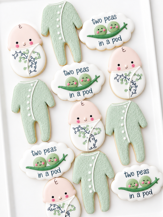 two peas in a pod, swaddled baby, crib mobile, footed pajamas, cat toy, baby shower cookies